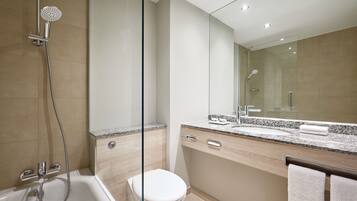 A modern bathroom with a glass shower enclosure, a white toilet, a granite countertop sink, and a large mirror.