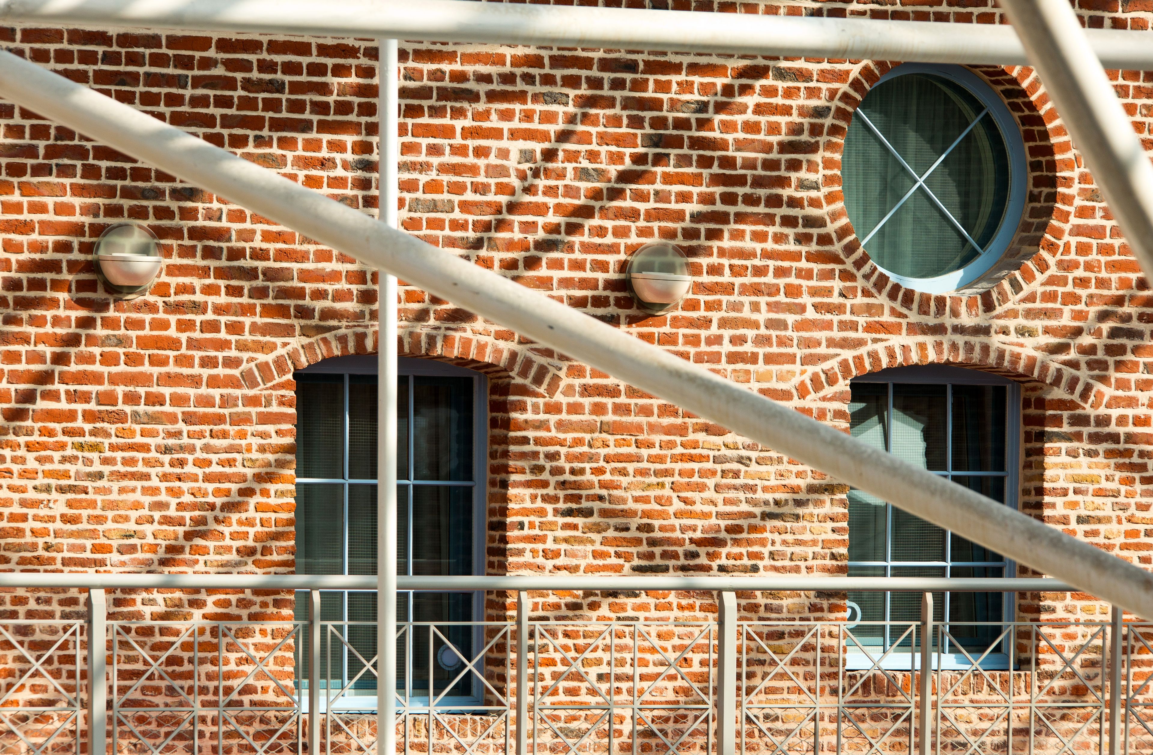 Ein Backsteinhaus mit einem Rundfenster und zwei Rechteckfenstern, umgeben von Gerüst.