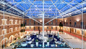 A spacious atrium with a glass ceiling, brick walls, and multiple seating areas.