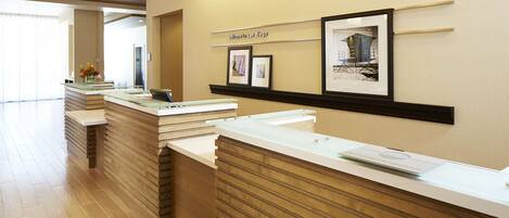 A reception area with a modern design, featuring a reception desk, a wall-mounted sign that reads "Welcome to San Diego," and framed pictures on the wall.