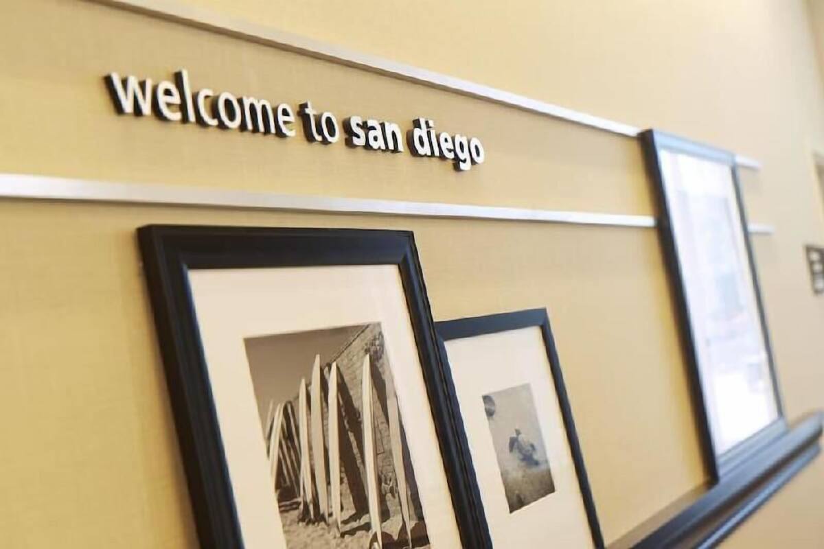A wall with a 'Welcome to San Diego' sign and framed historical photos.