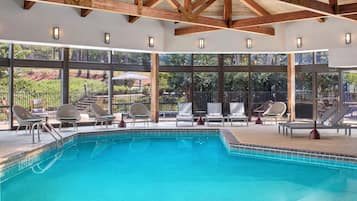 A swimming pool with lounge chairs and a view of the outdoors.