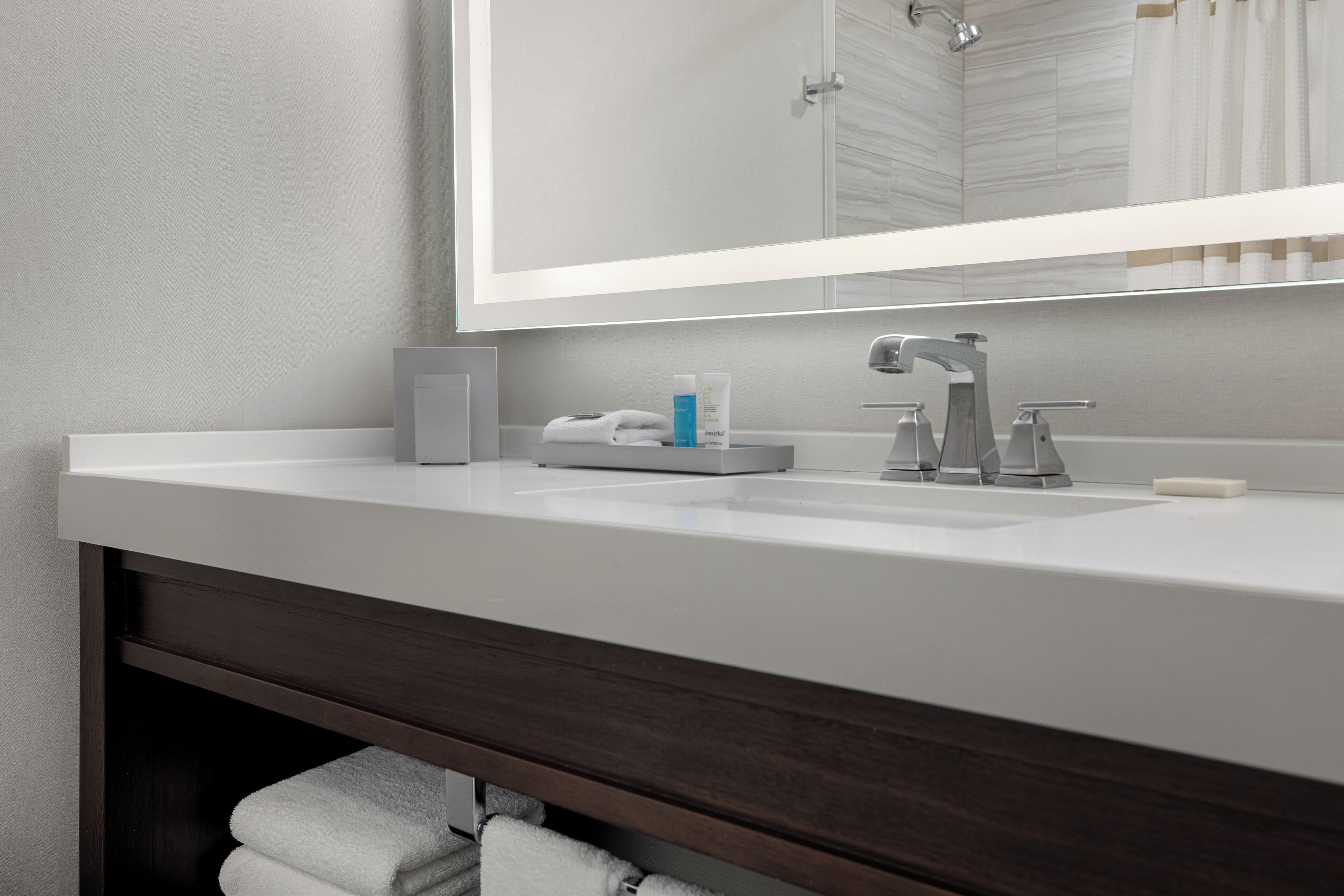 Une salle de bain moderne avec un lavabo blanc, un miroir et un meuble-lavabo en bois foncé.