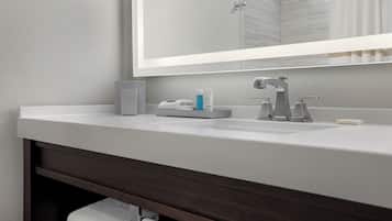 Une salle de bain moderne avec un lavabo blanc, un miroir et un meuble-lavabo en bois foncé.