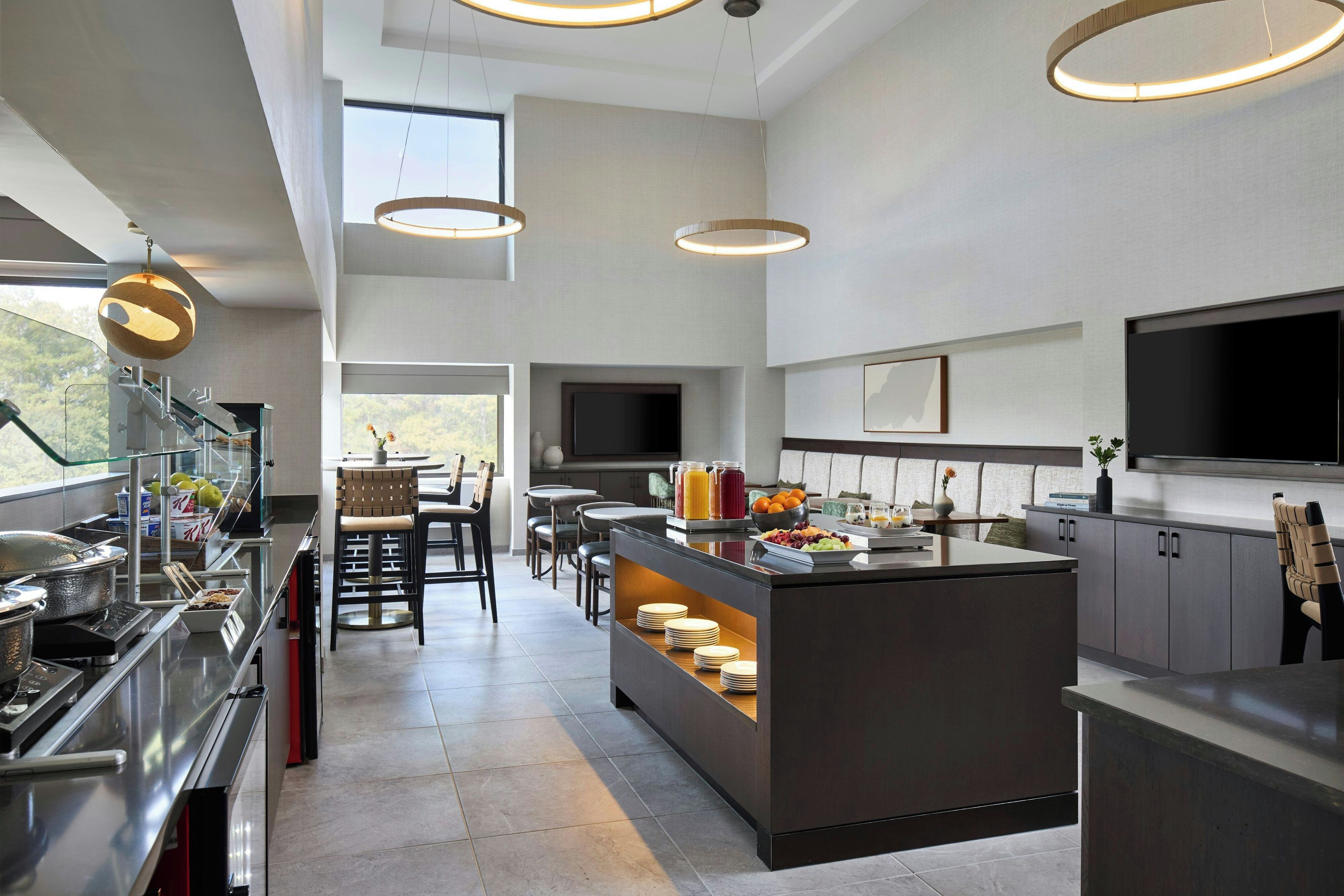 A modern kitchen with a central island, built-in appliances, and a dining area with chairs and tables.