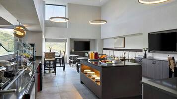 A modern kitchen with a central island, built-in appliances, and a dining area with chairs and tables.