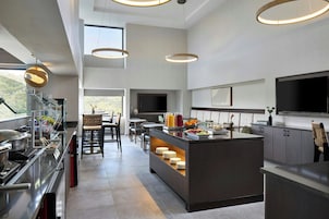 A modern kitchen with a central island, built-in appliances, and a dining area with chairs and tables.