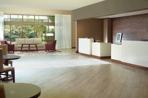 Un vestíbulo espacioso con mostrador de recepción, zona de estar y grandes ventanales con vistas al exterior.