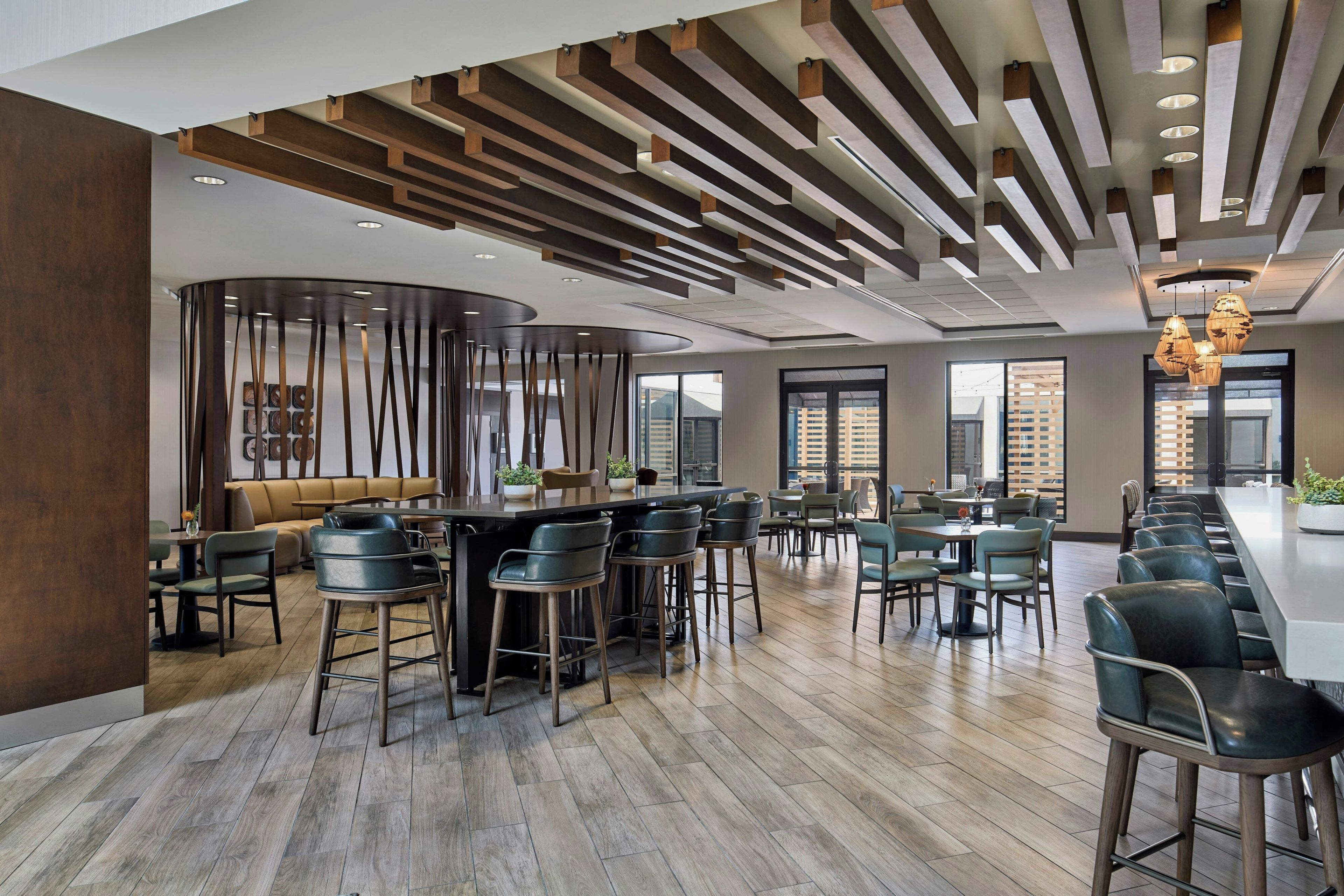 A modern interior with a bar area, seating, and large windows.