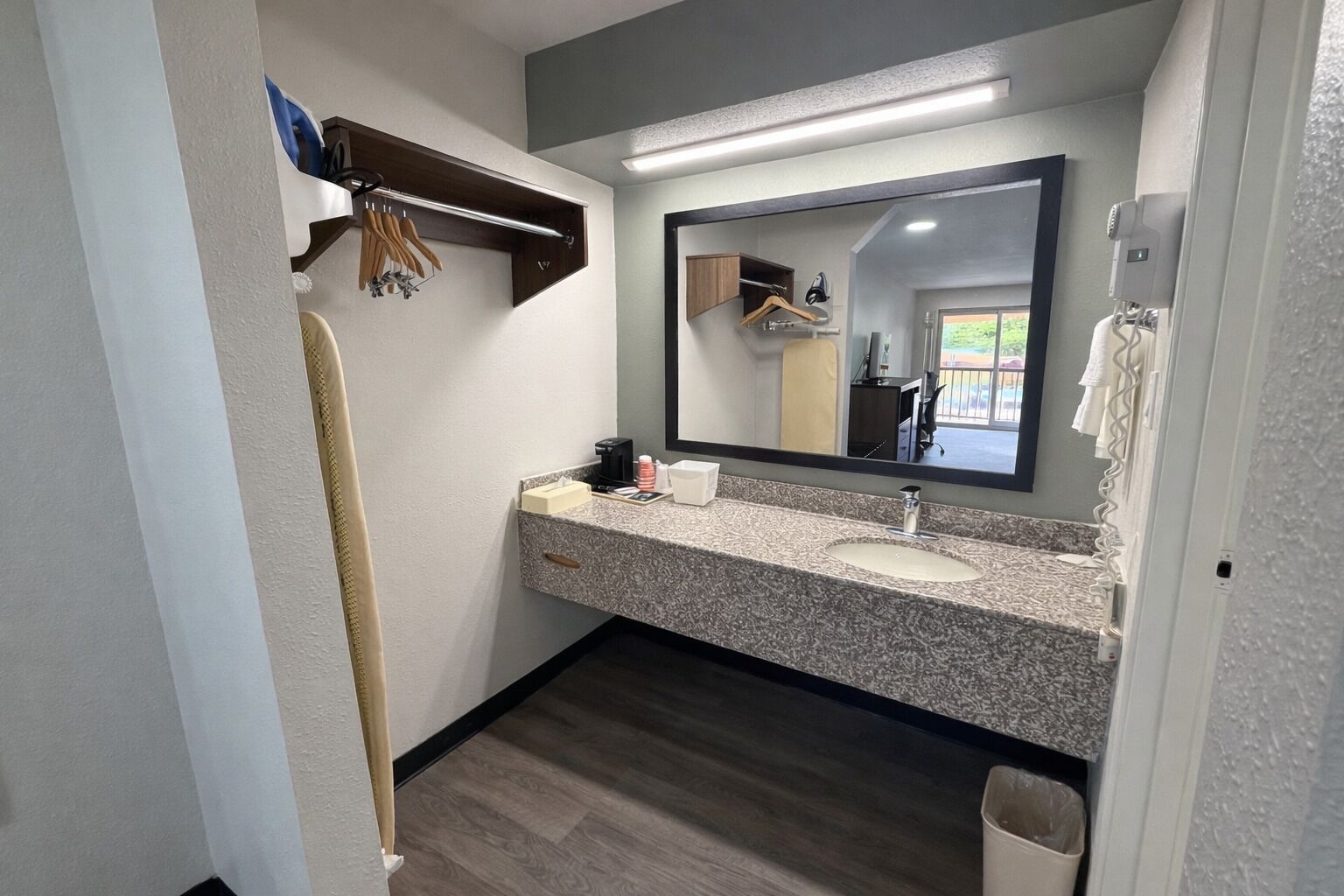 A bathroom with a granite countertop, a sink, a mirror, a towel rack, and a wooden floor.