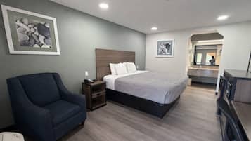 Een hotelkamer met een bed, een stoel, een nachtkastje en een bureau.