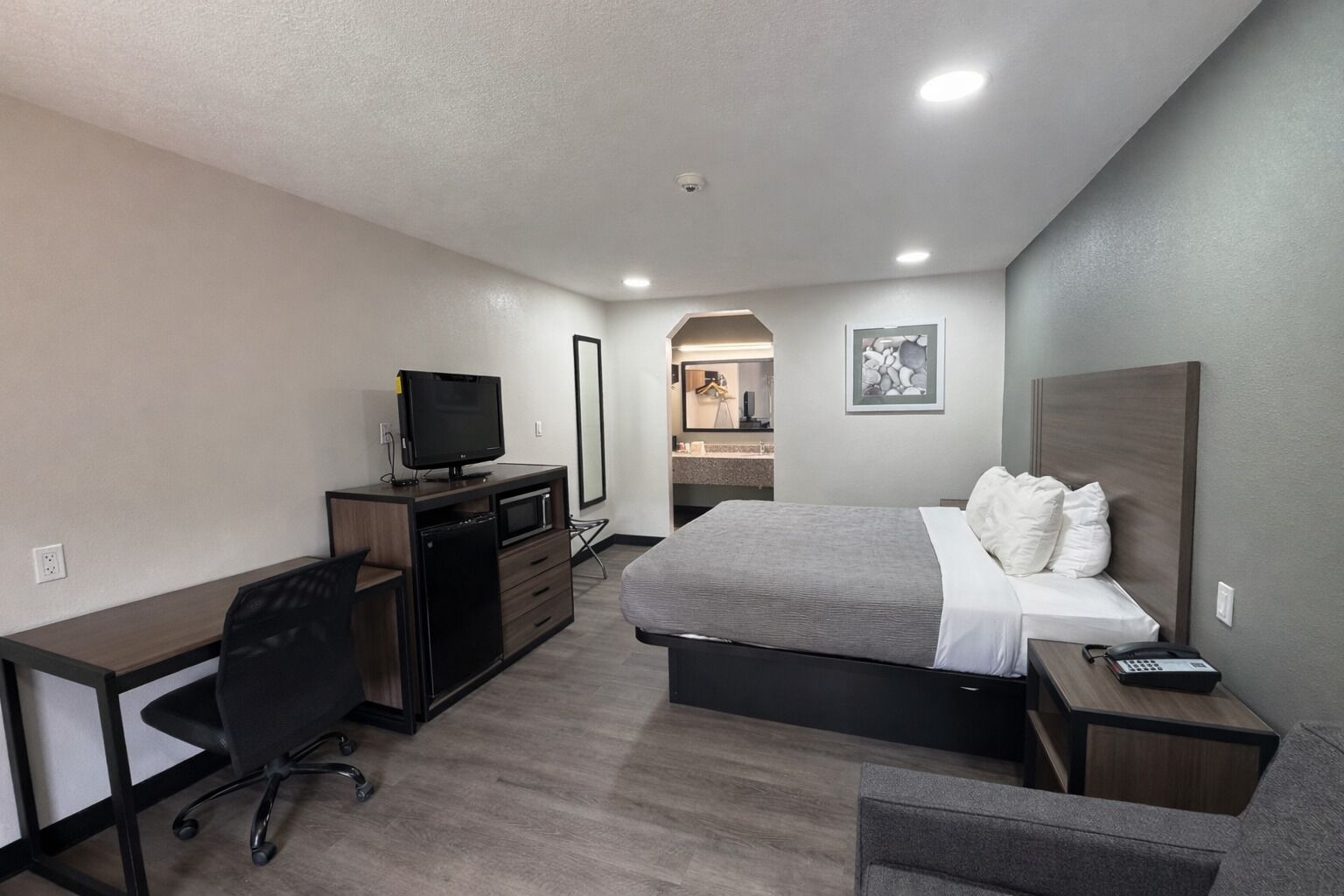 Une chambre d’hôtel avec un lit, un bureau, une télévision, et une salle de bain visible au fond.