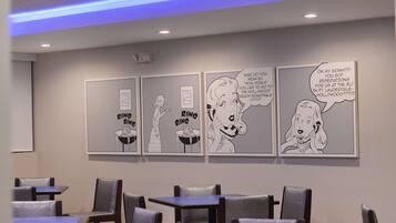 A restaurant interior with comic strip artwork on the wall, tables, and chairs.