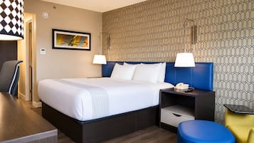 Habitación de hotel con una cama grande, dos mesitas de noche, un escritorio y una silla.