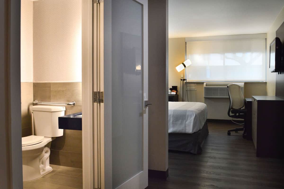 Una camera d'albergo con il bagno, un letto, una scrivania e una sedia.