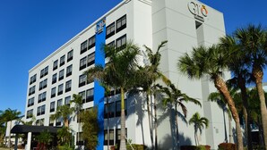 Un moderno edificio hotel con una facciata importante in blu e bianco, diversi piani e palme sullo sfondo.