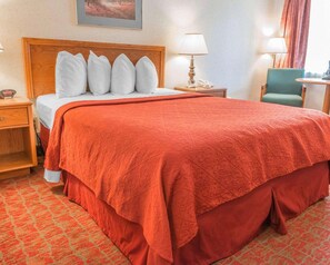 Relax in comfort with a large bed, wooden headboard, and plush carpeting.