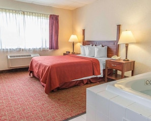 Una habitación de hotel con cama, lámparas de noche, teléfono, escritorio y bañera.
