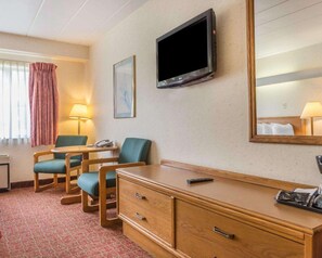 A hotel room with a wooden desk, two chairs, a TV, a mirror, a lamp, and a telephone. - Quality Inn Royle (Kittanning)