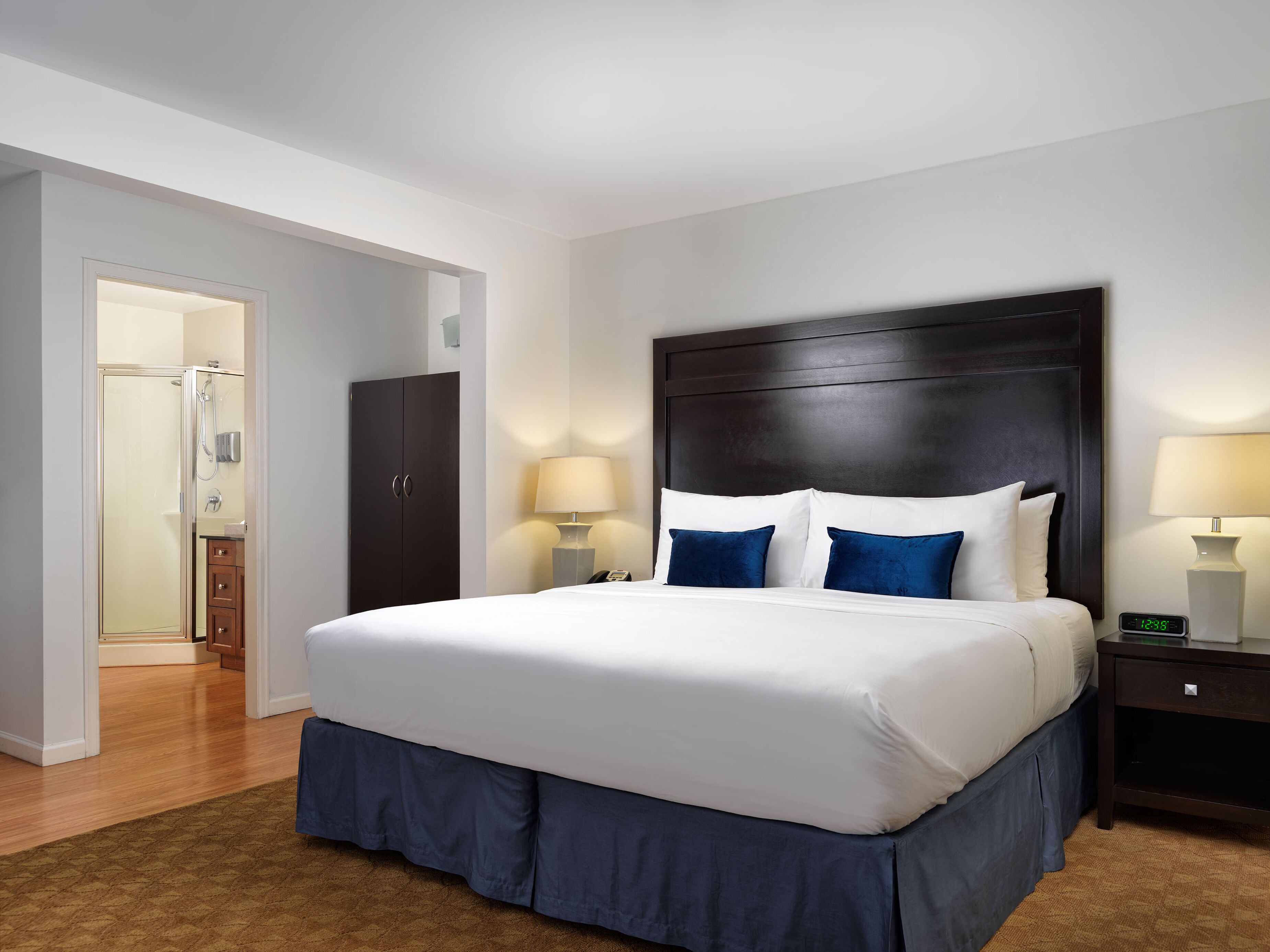 A hotel room with a large bed, bedside lamps, a wardrobe, and a shower area.