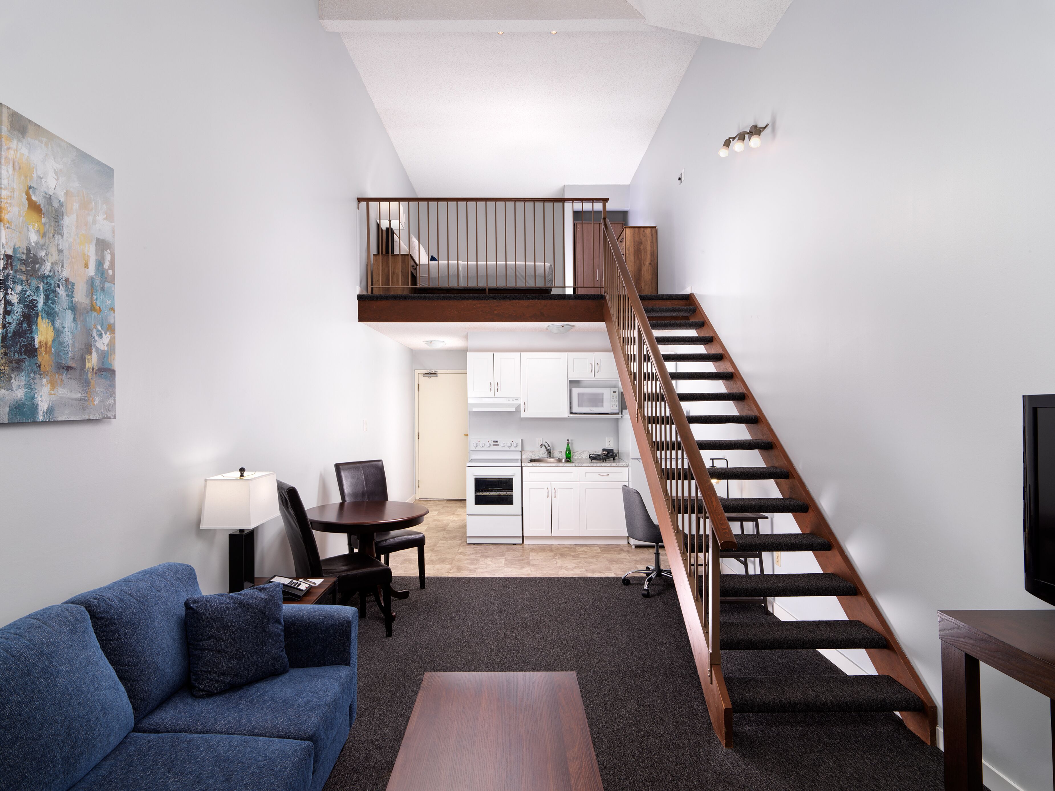 Un apartamento moderno con sala de estar, comedor, cocina y una escalera que conduce a un nivel superior.