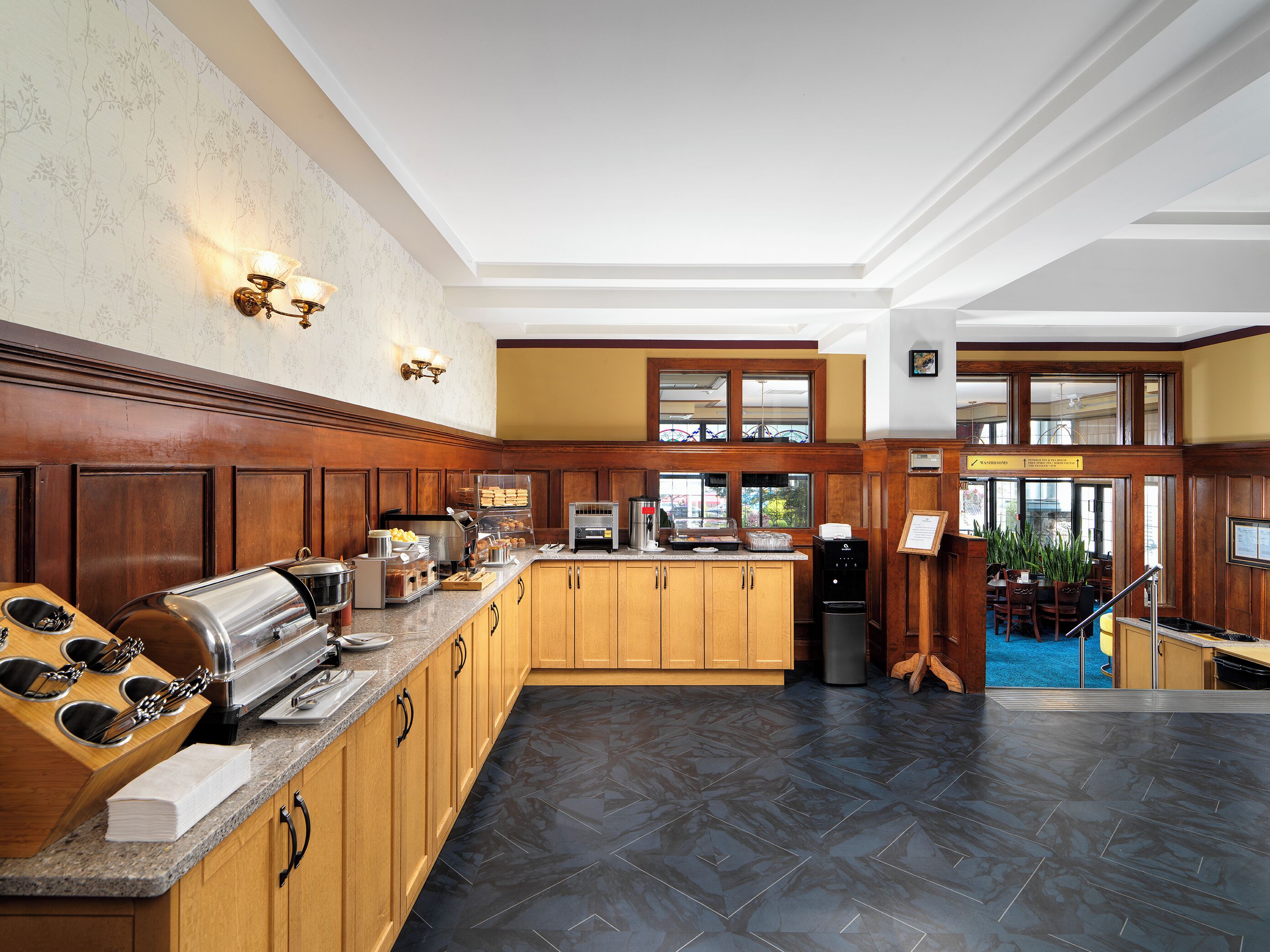 A modern kitchen with wooden cabinetry, a built-in stove, and a coffee station.
