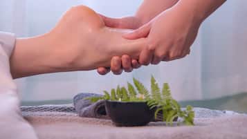 A foot massage with a towel and a small potted plant on a massage table.
