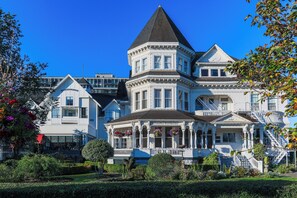 A large, white Victorian-style building with a prominent tower and a wrap-around porch.