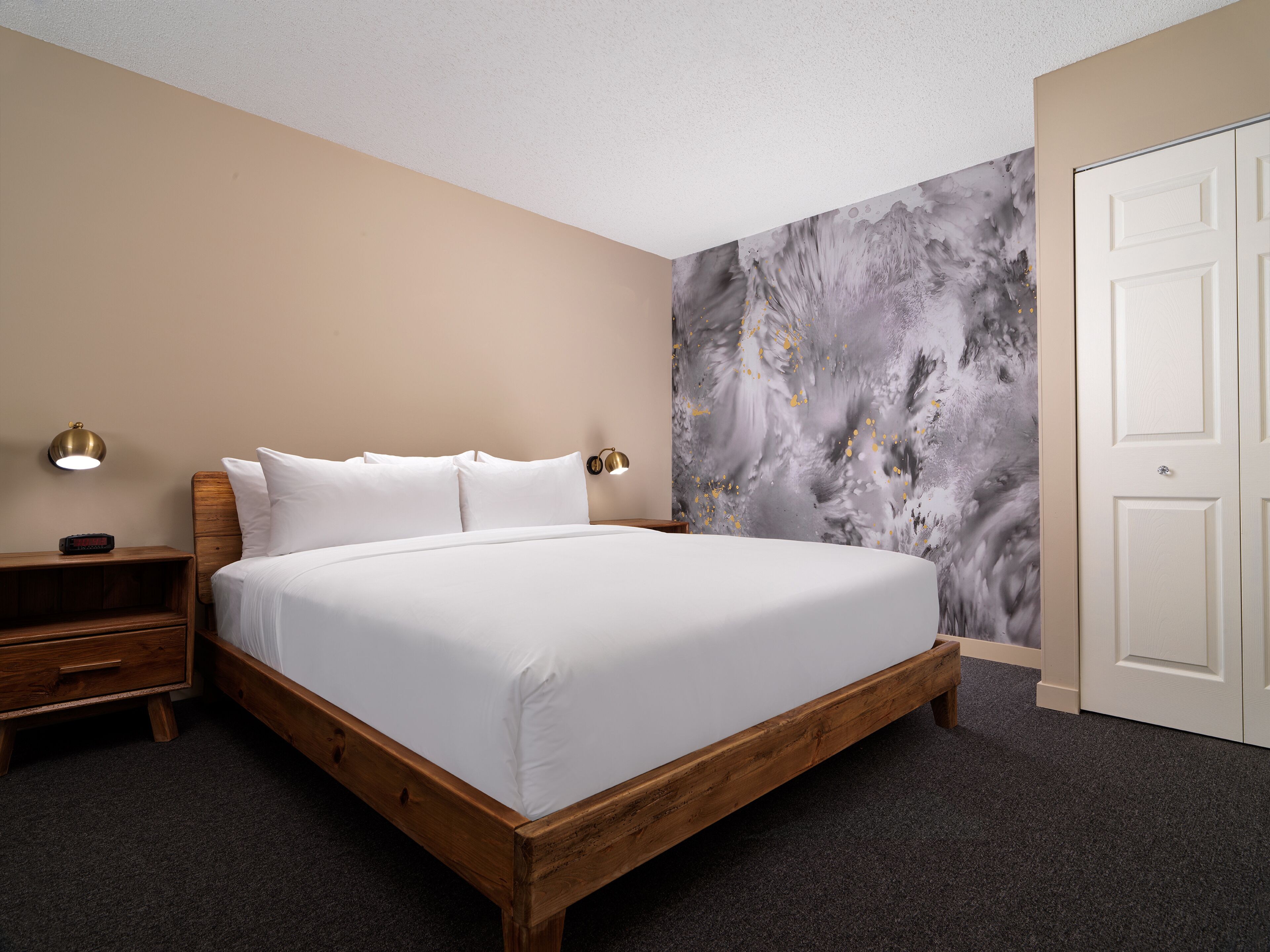 A neatly made bed with white linens, a wooden headboard, and two bedside lamps.