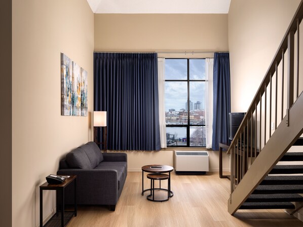 Relax in this stylish living room with a sofa, table, and chair, plus a large window and staircase.