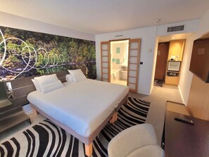 Habitación de hotel con cama, escritorio, silla, baño y televisión.