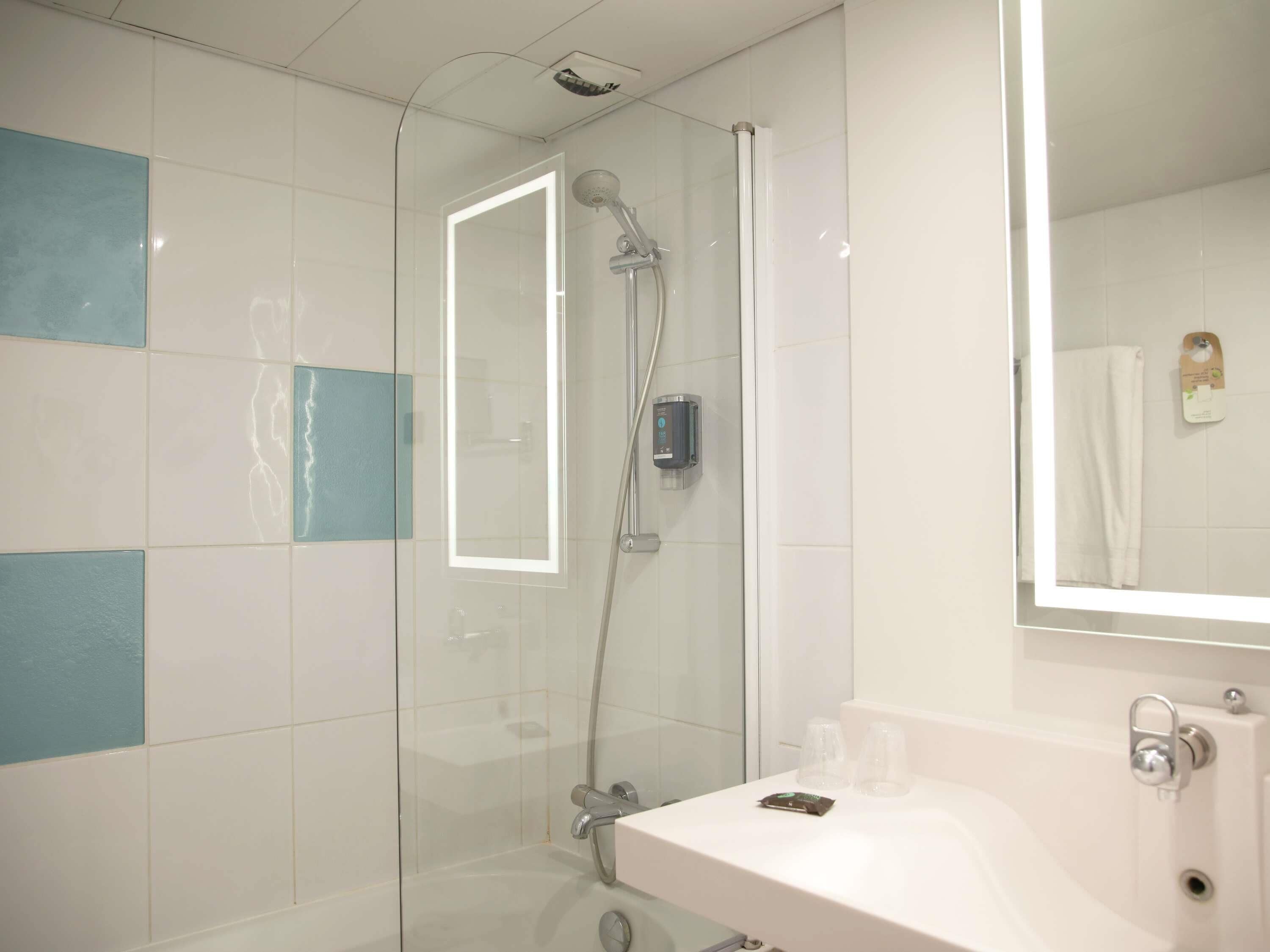 A modern bathroom with a glass-enclosed shower, a white sink, and a mirror.