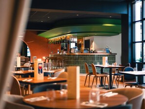 A restaurant with a curved counter, bar area, and several tables with chairs. - Novotel Lille Centre Grand Place (Lille)