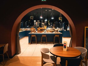 A restaurant with a central island counter, bar stools, and hanging plants. - Novotel Lille Centre Grand Place (Lille)