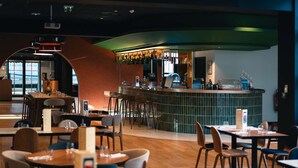 Ein Restaurant mit Barbereich, Holztischen und -stühlen.