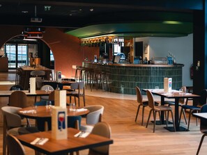 A restaurant with a bar area, wooden tables, and chairs. - Novotel Lille Centre Grand Place (Lille)
