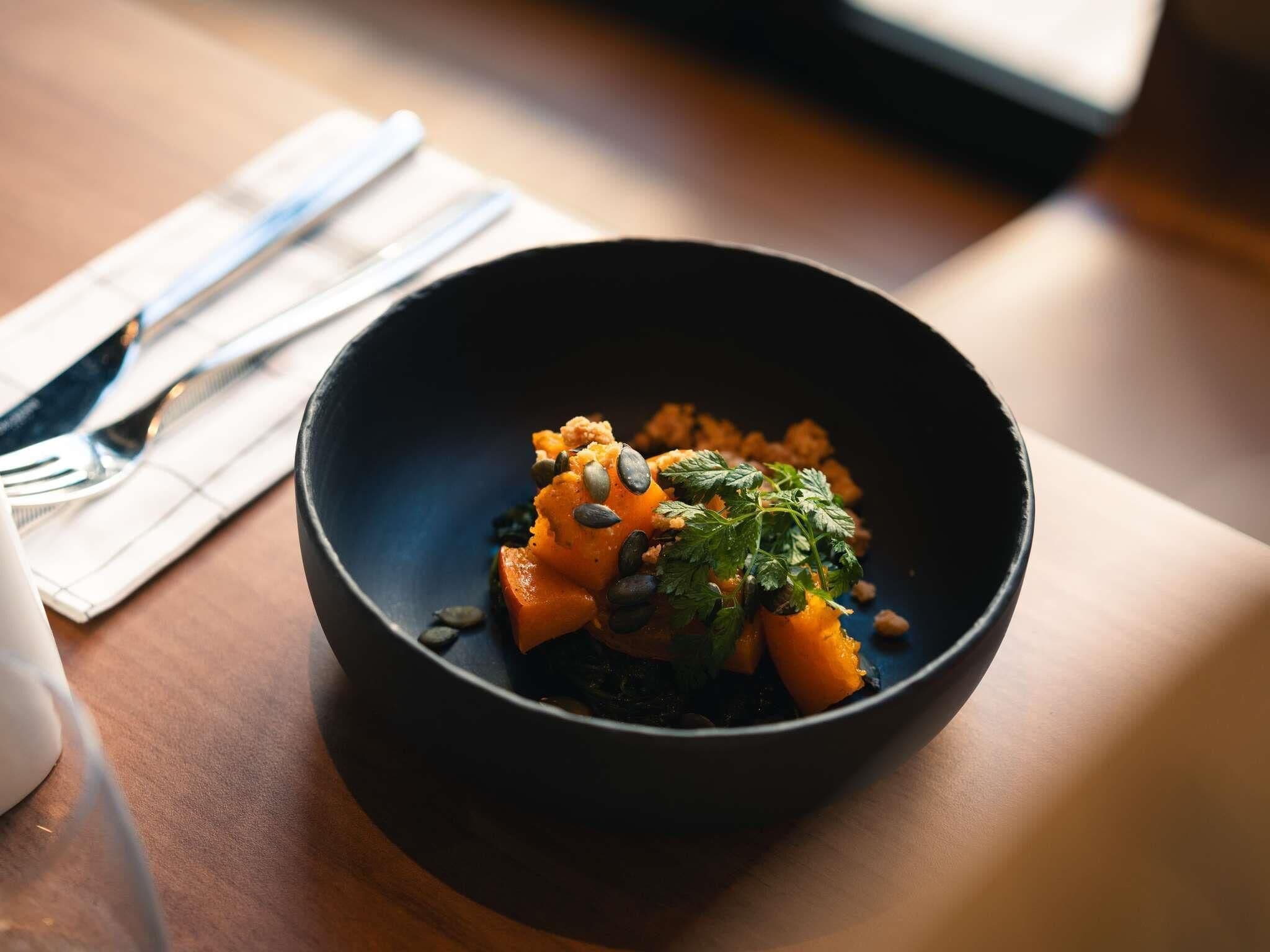 A dark bowl with food on a table.