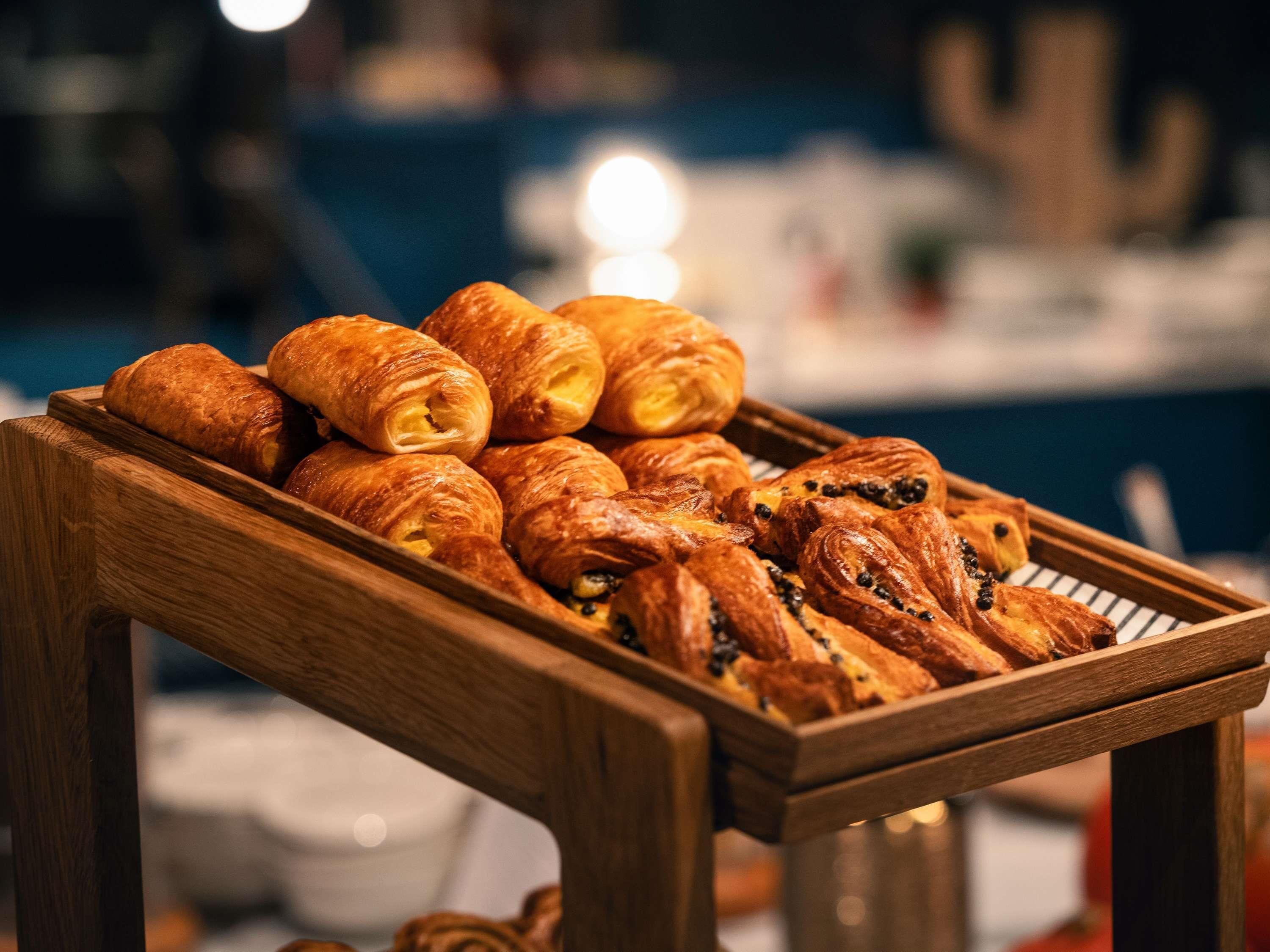 A wooden tray with assorted pastries, including croissants and chocolate-filled ones.