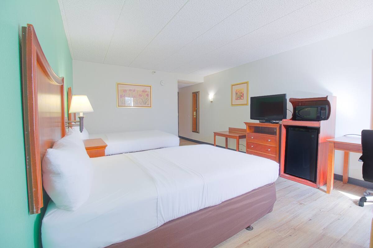 A hotel room with a bed, a desk, a television, and a microwave.