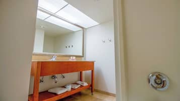 Een badkamer met een houten wastafelmeubel, een grote spiegel en een handdoekrek.
