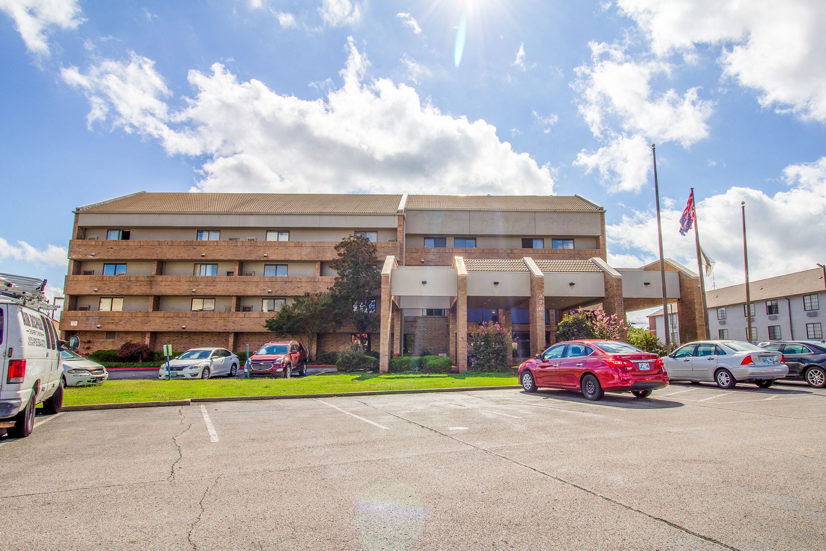 A multi-story hotel with a parking lot in front.