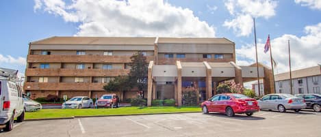 Un hotel de varios pisos con un estacionamiento al frente.