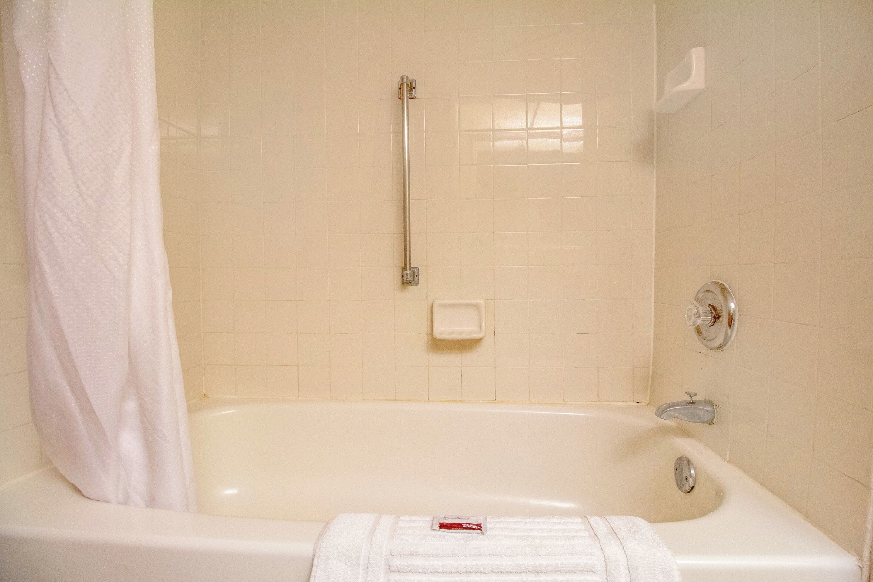 Une salle de bain équipée d’une baignoire, d’un rideau de douche, d’une barre d’appui et d’un porte-savon.