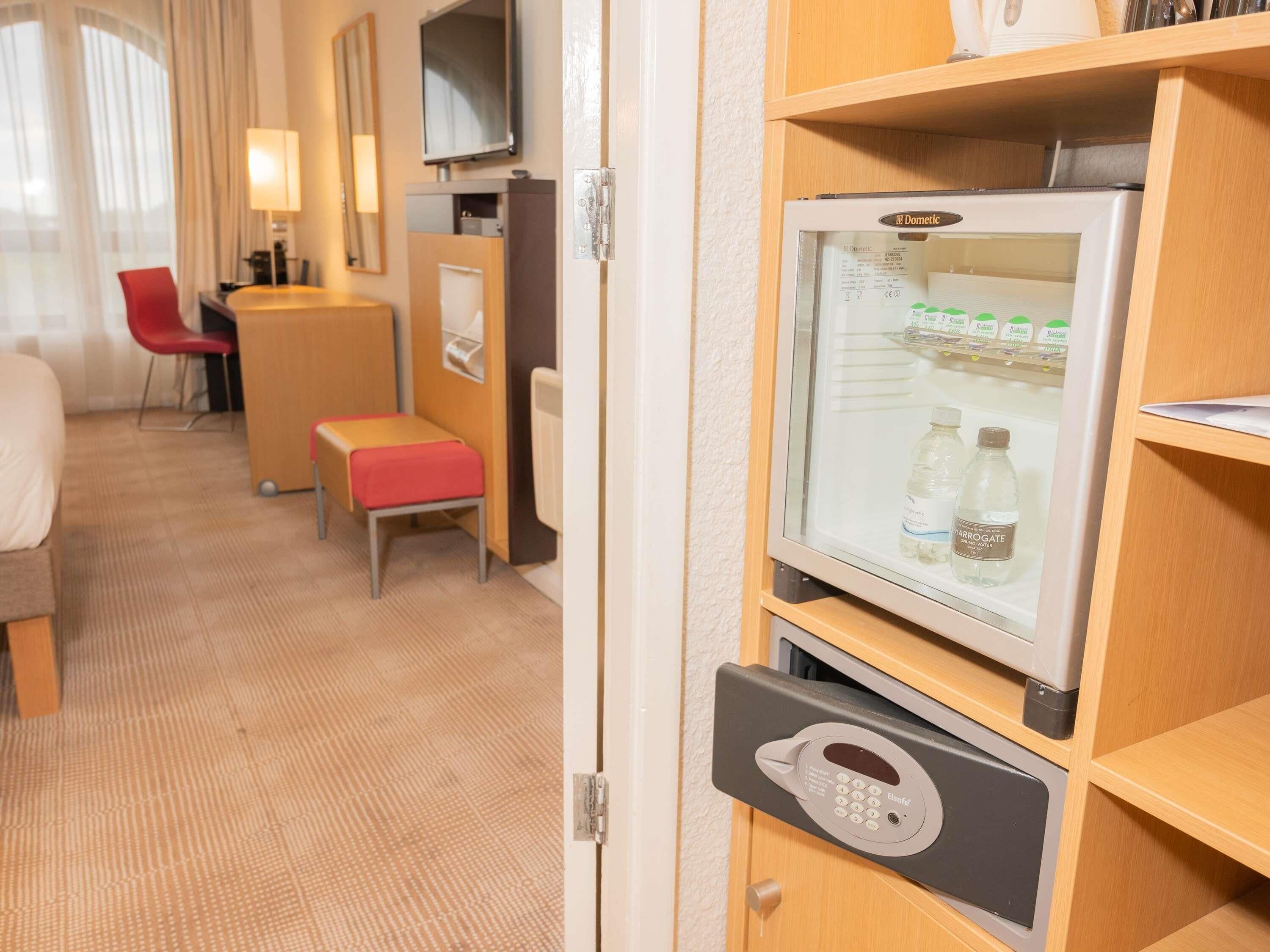 Ein Hotelzimmer mit Minibar, Fernseher, Schreibtisch mit Stuhl und einer kleinen Sitzecke.