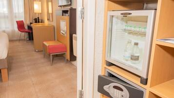 Ein Hotelzimmer mit Minibar, Fernseher, Schreibtisch mit Stuhl und einer kleinen Sitzecke.