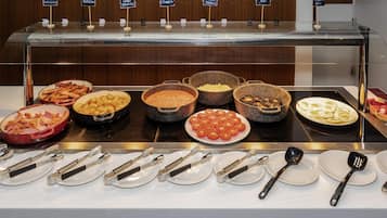 Um buffet com diversos alimentos e utensílios.