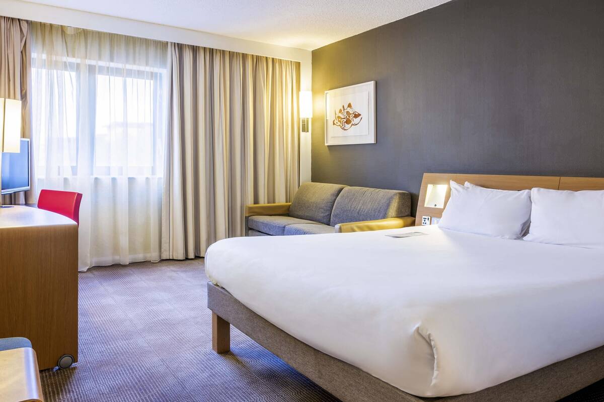 Een hotelkamer met een groot bed, een bureau, een stoel en een bank.
