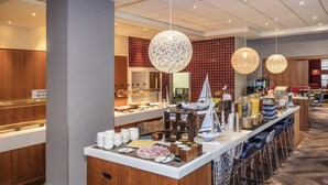 A hotel breakfast area with a buffet, bar seating, and decorative elements like model ships.