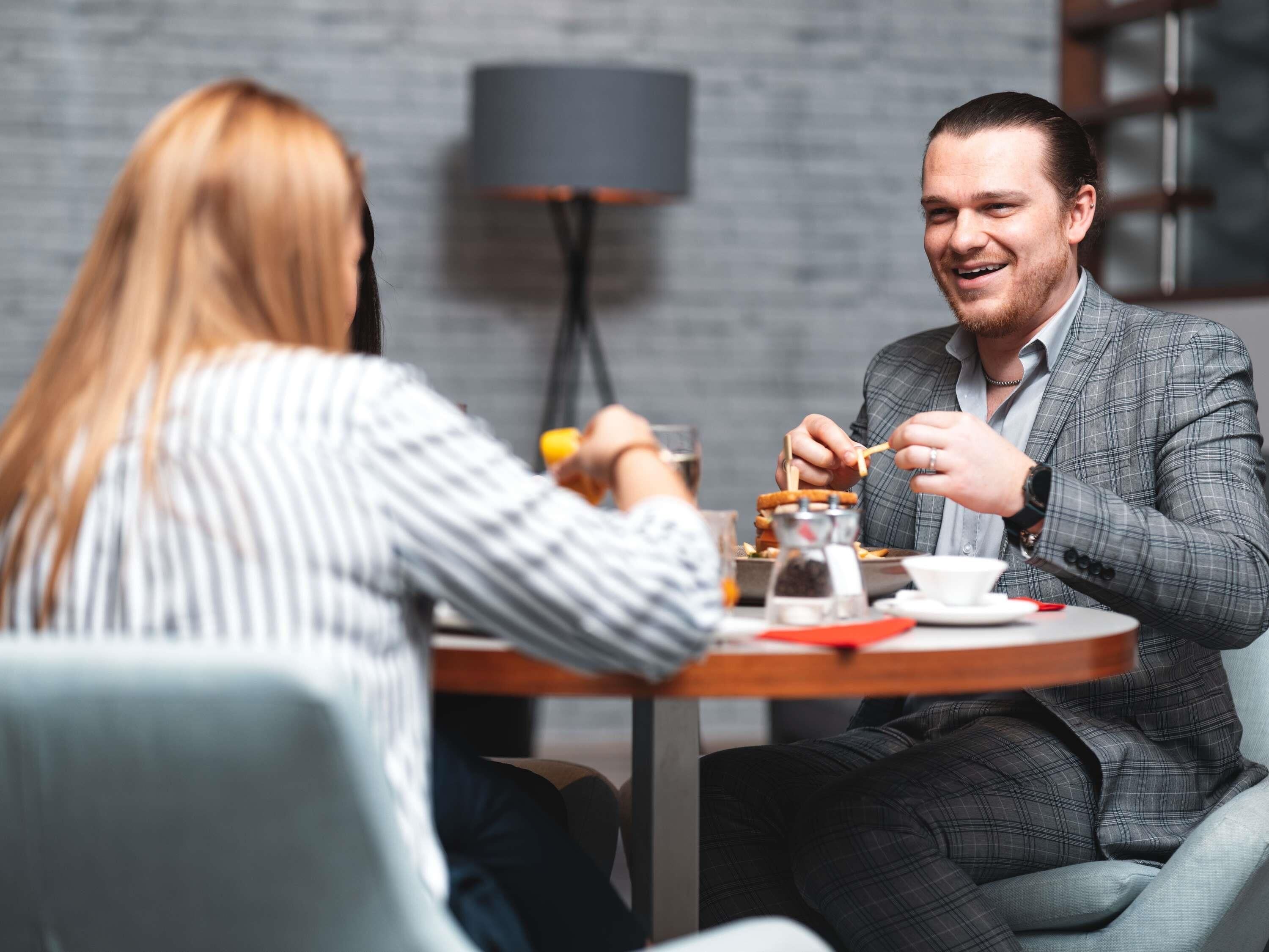 Two people dining at a round table with a lamp in the background.