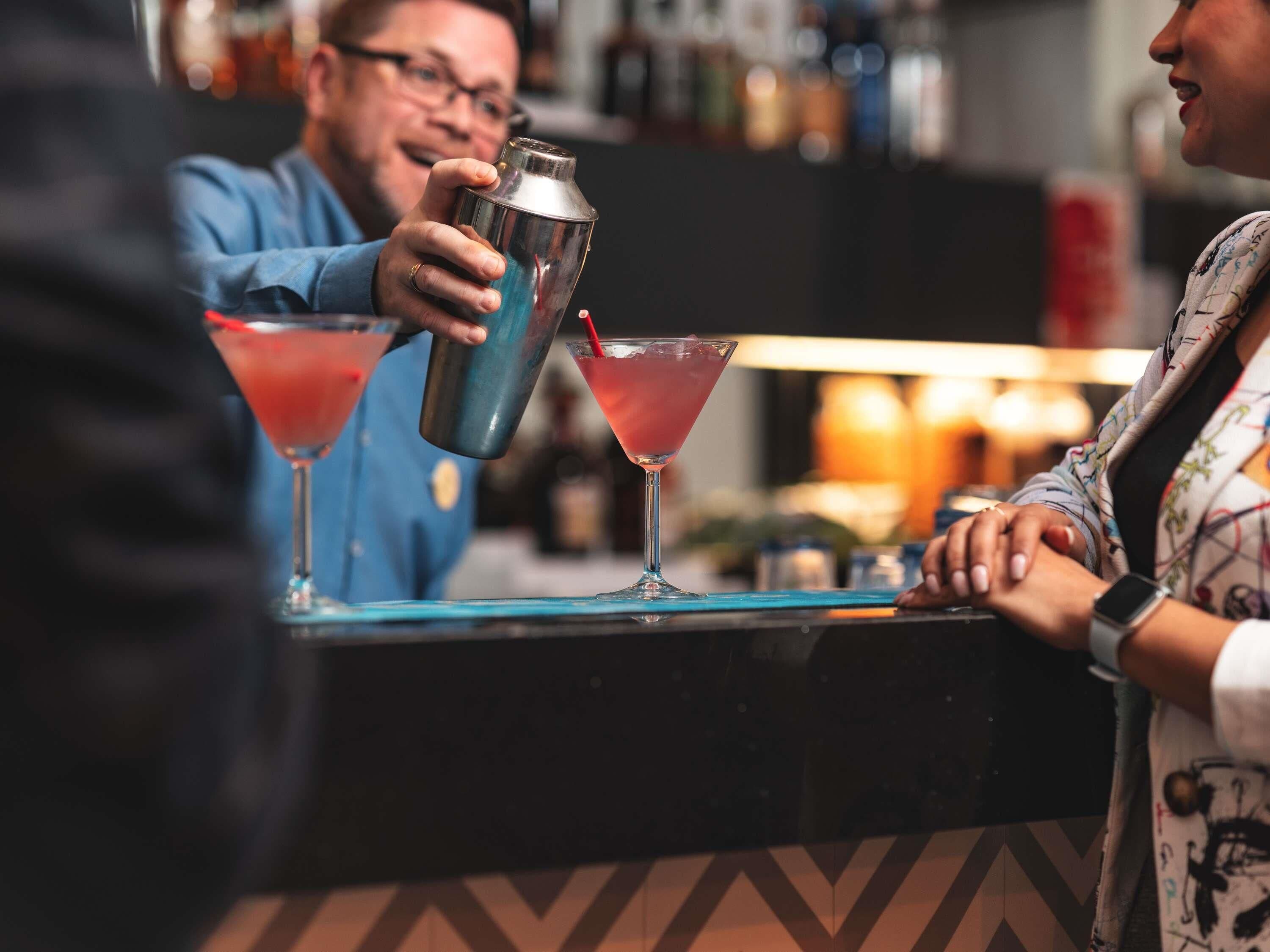 A bar setting with a bartender preparing drinks.